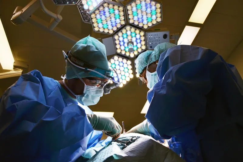 Surgeons in gloves and gowns operating under theatre lights