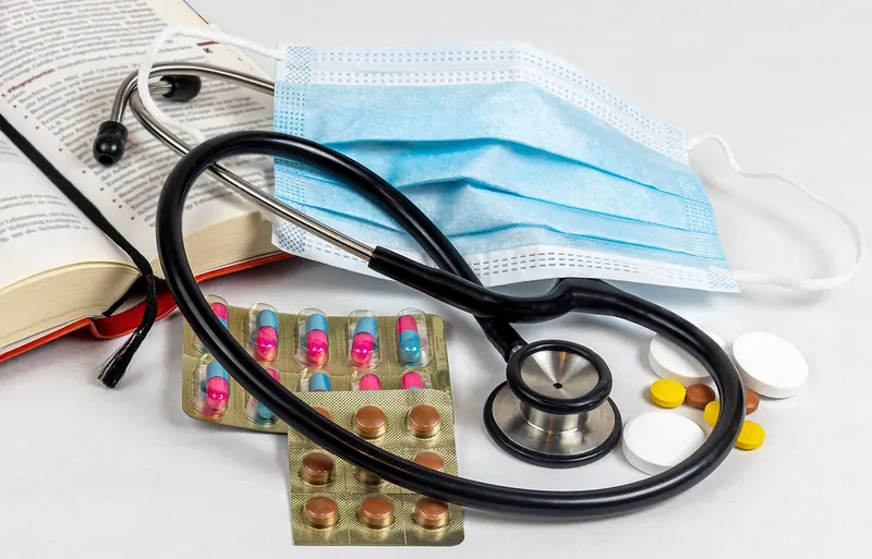 Stethoscope, face mask and blister packs of tablets on a table